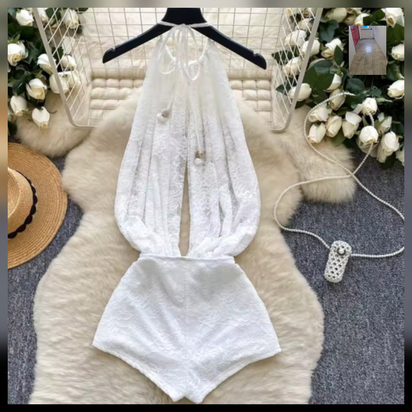 White textured halter top romper displayed on a hanger against a backdrop of roses.