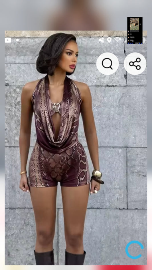 Classy romper with gold detail worn by model against a stylish, textured background.