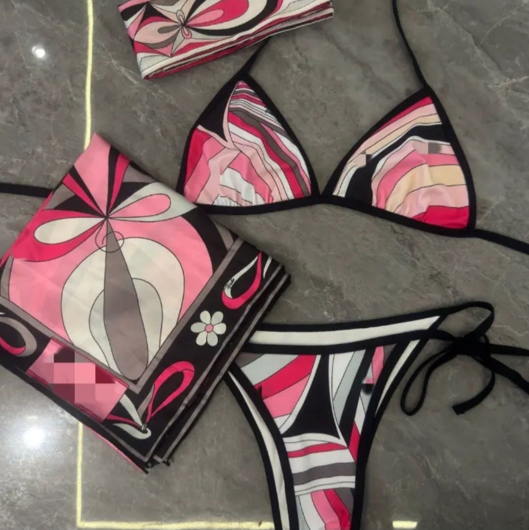 Swirl bikini with scarves featuring matching designs and colors, displayed on a marble surface.