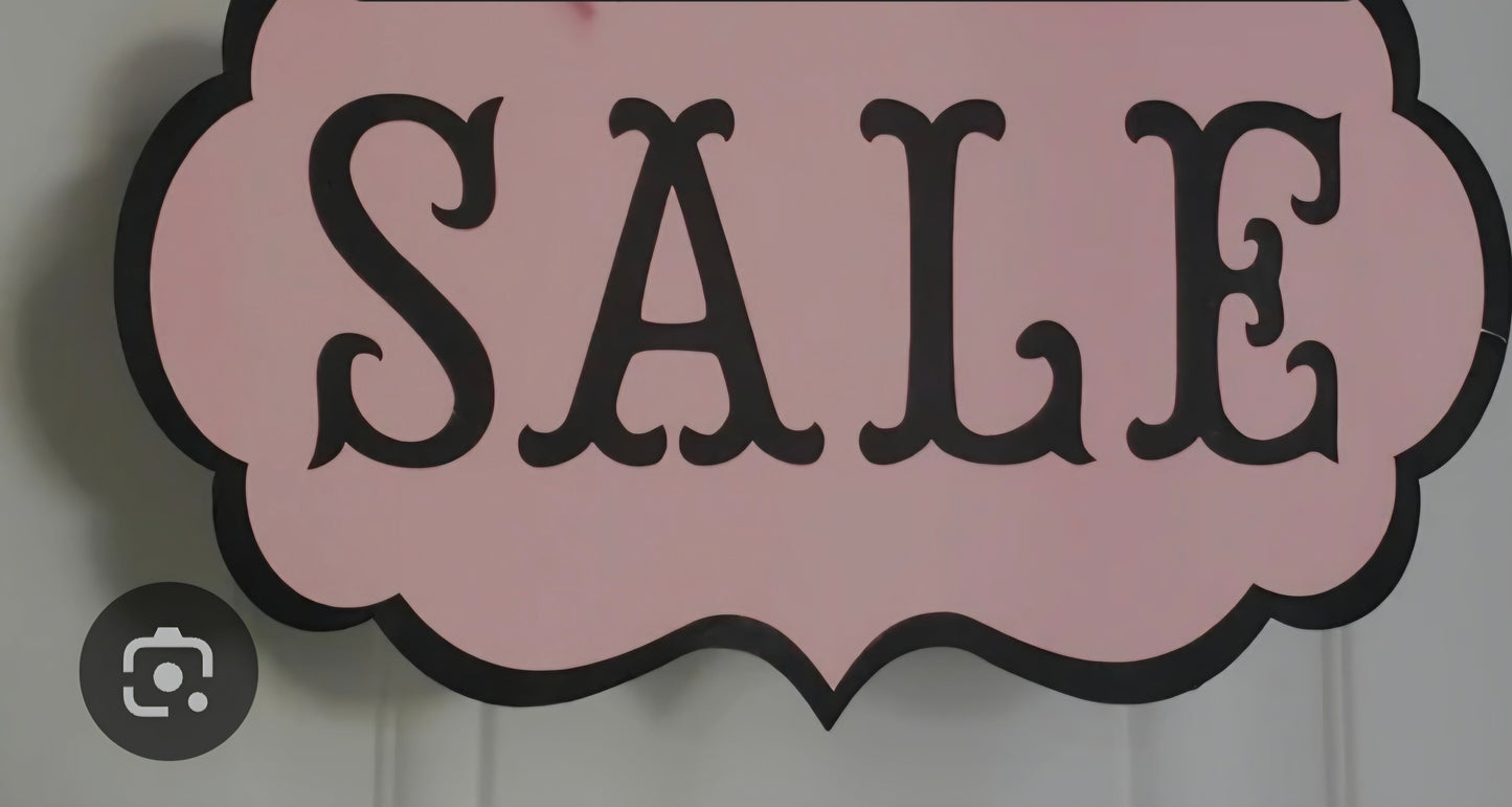 Sale sign promoting budget outfits for $100 with pink background and bold letters.