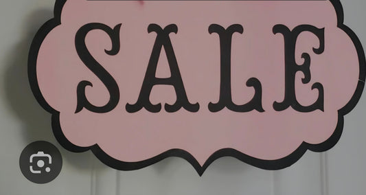 Sale sign promoting budget outfits for $100 with pink background and bold letters.